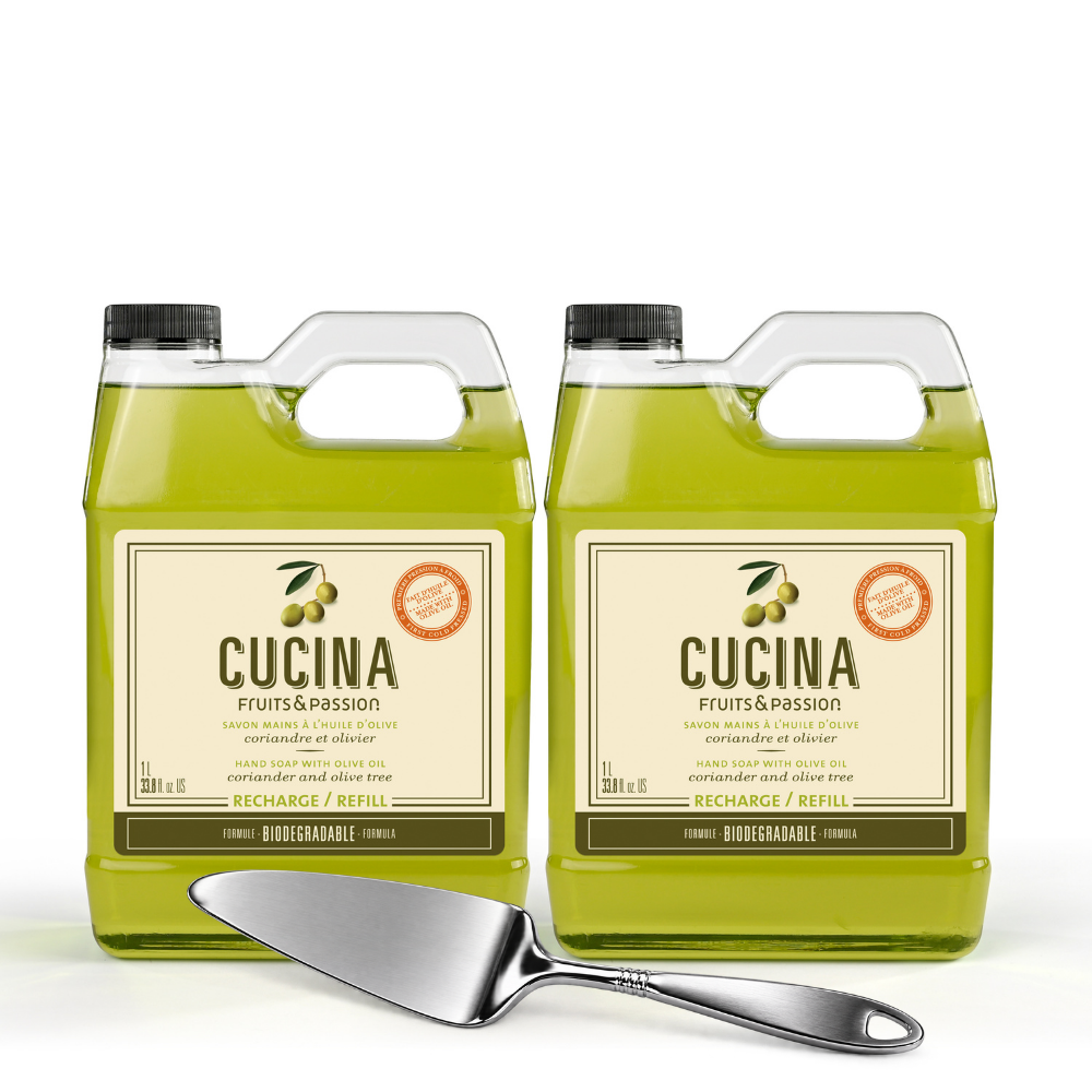 Two large plastic jugs of CUCINA Fruits & Passion olive oil with black caps and beige labels, shown side by side on a white background with a metal serving spatula in front.