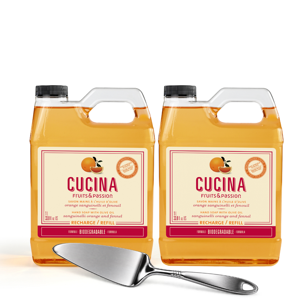Two large plastic jugs of CUCINA Fruits & Passion citrus-infused cooking oil with a stainless steel serving spoon in front, on a clean white background.